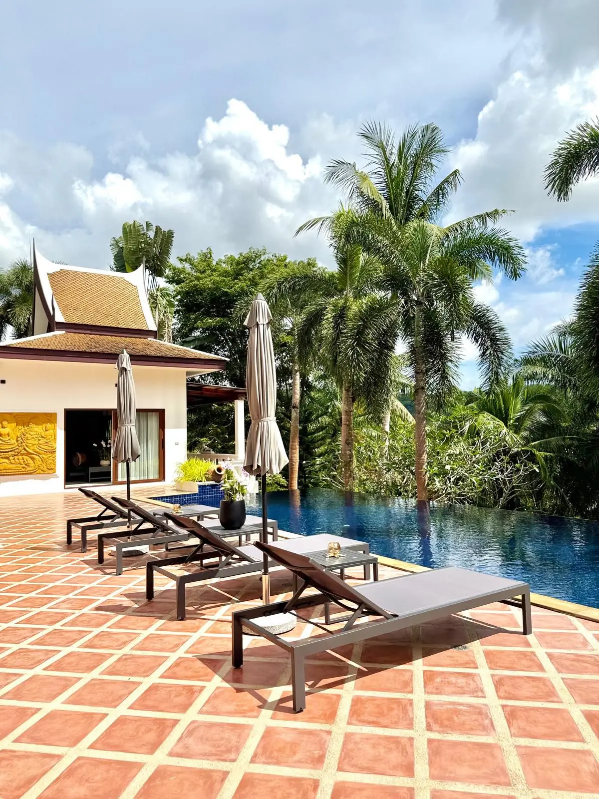 Pool sun terrace with carved Thai sala visible across the deck
