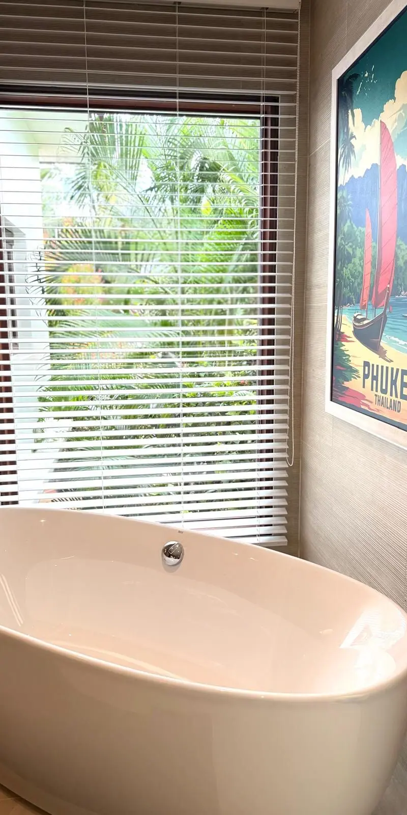 Guest bathroom with freestanding bathtub and vintage Phuket travel poster