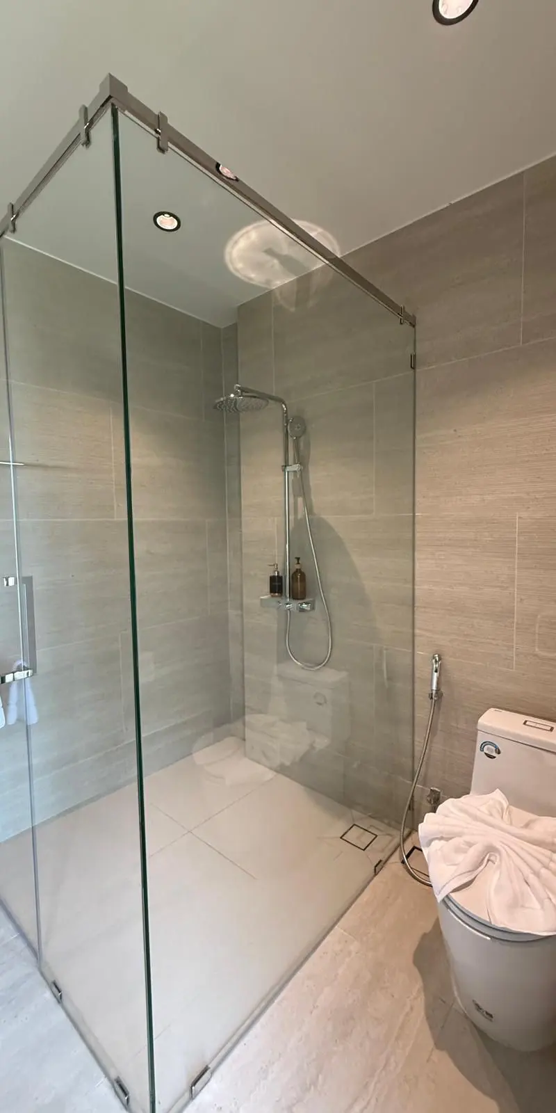 Guest bathroom with large frameless walk-in shower in pale marble