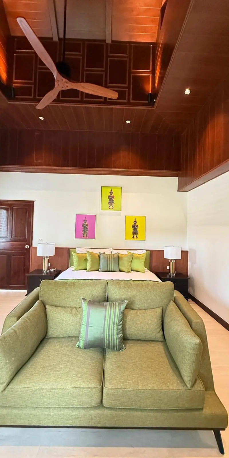 Guest bedroom with three framed Thai puppet panels and olive love-seat