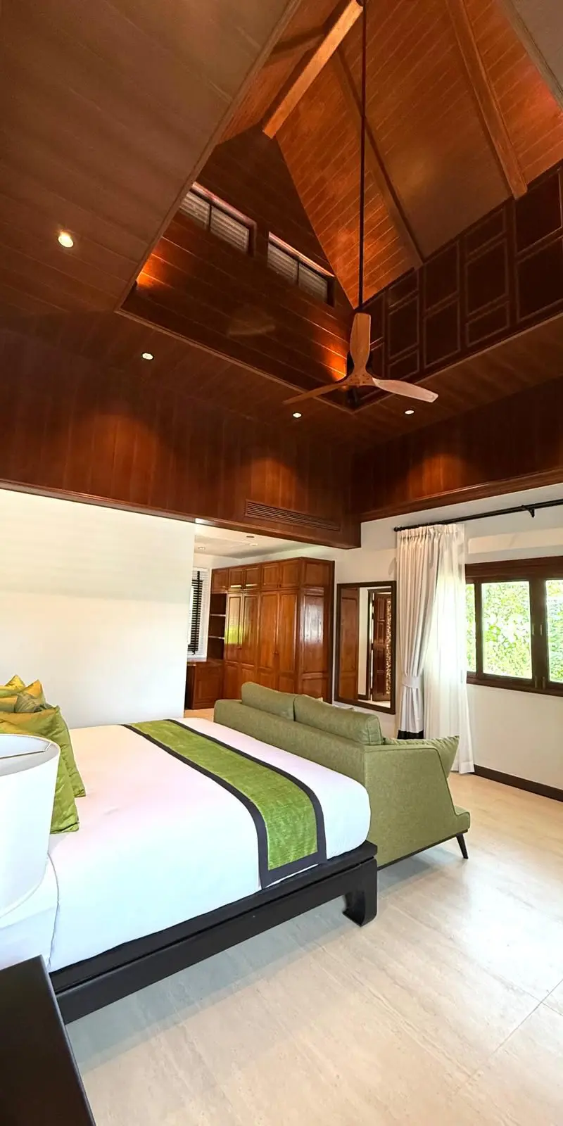 Guest bedroom with green velvet headboard and high cathedral wooden ceiling