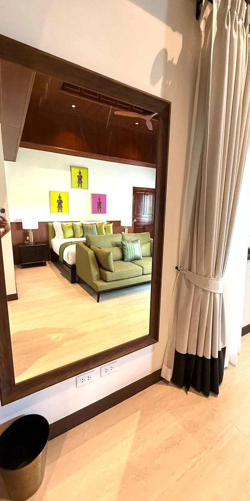 Tall wood-framed mirror reflecting the bedroom suite