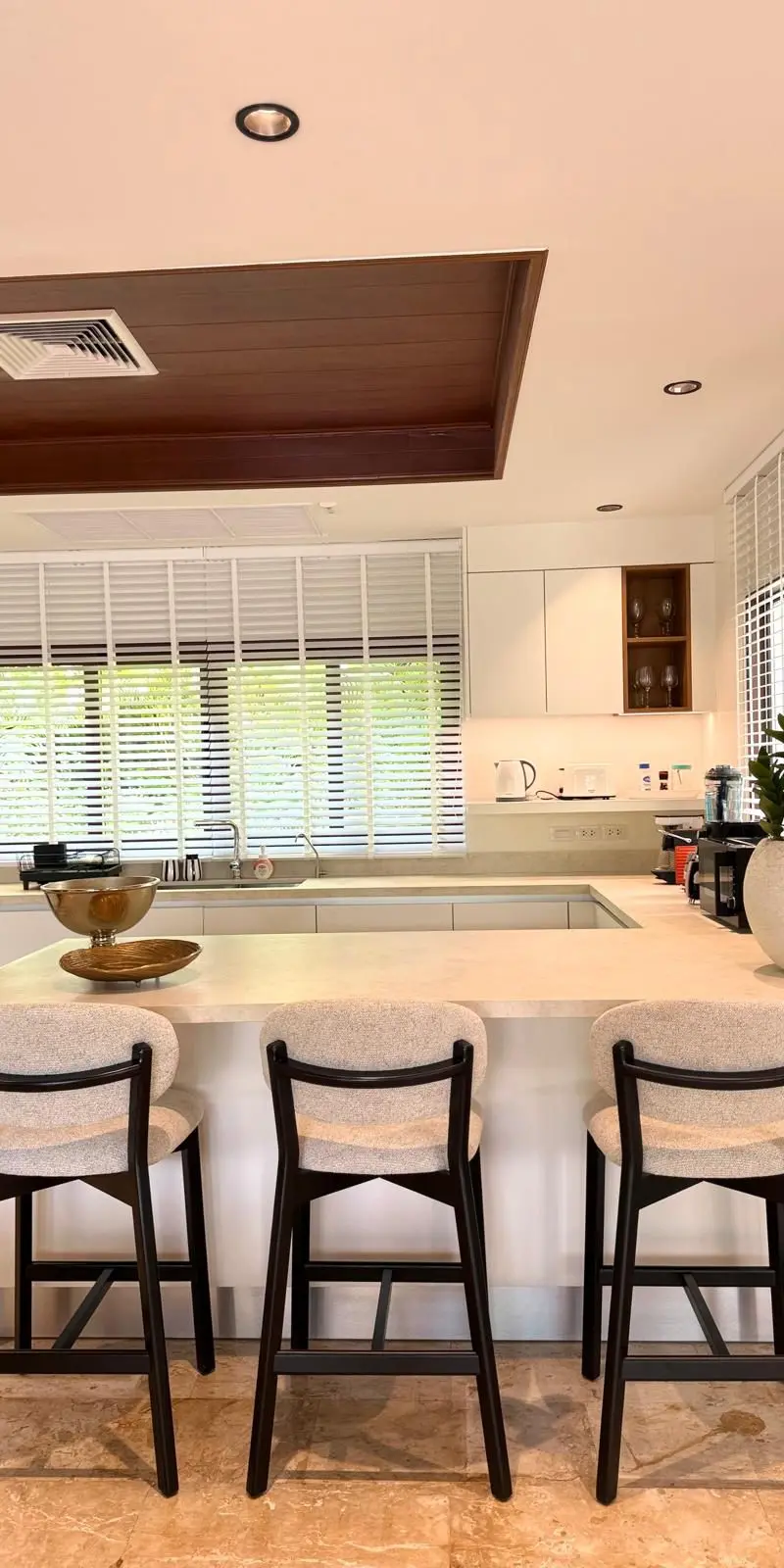 Open kitchen with stone-island breakfast bar and three counter stools