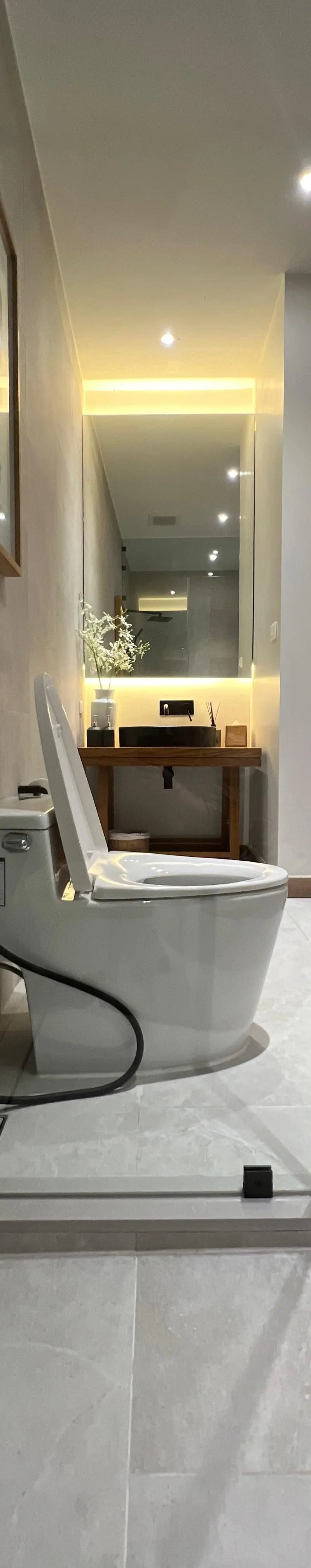 Guest bathroom with glass-enclosed toilet between two stone walls