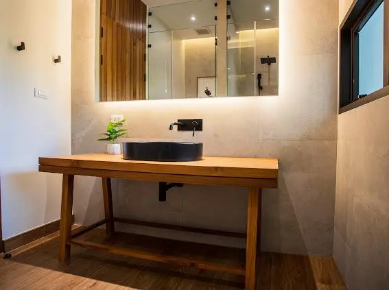 Powder room with wood-top vanity, black vessel sink and framed art