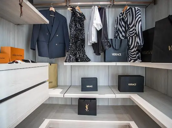 Walk-in closet hanging area with suits, dresses and designer accessories