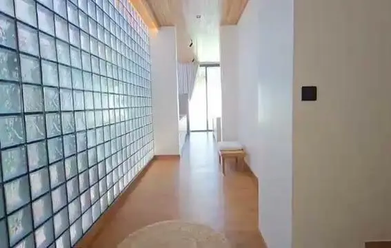 Hallway with glass-block wall, wood floor and bench-stool