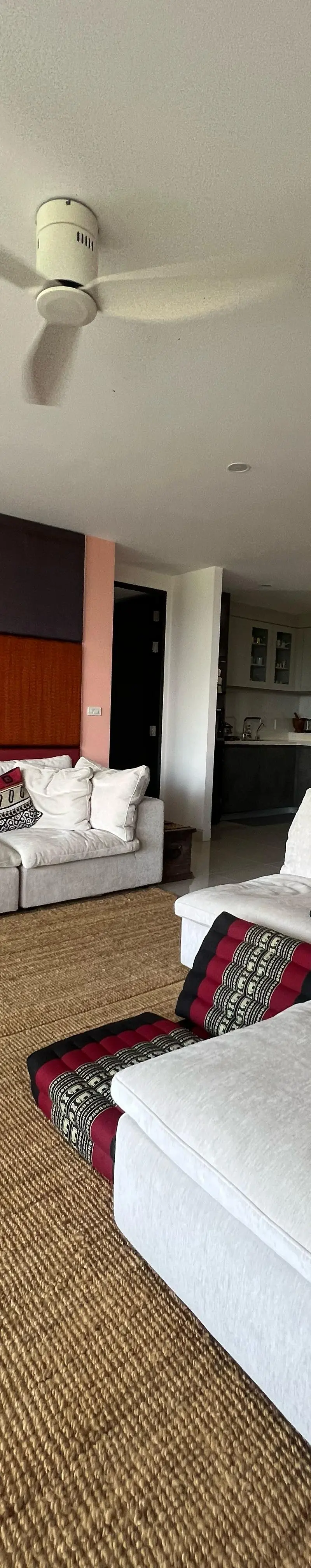 Open living room with sectional sofa and Thai art panels