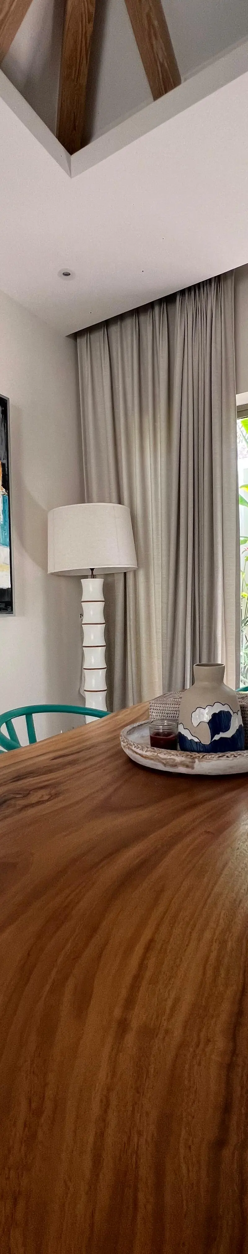 Dining area with live-edge wood table, teal armchairs and abstract canvas